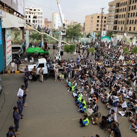 Members of Yemen's security forces stand guard as as Shiite Muslims listen to a speech by Houthi leader Abdul-Malik al-Huthi broadcast on a giant screen during a ceremony commemorating Ashura, July 16, 2024. 